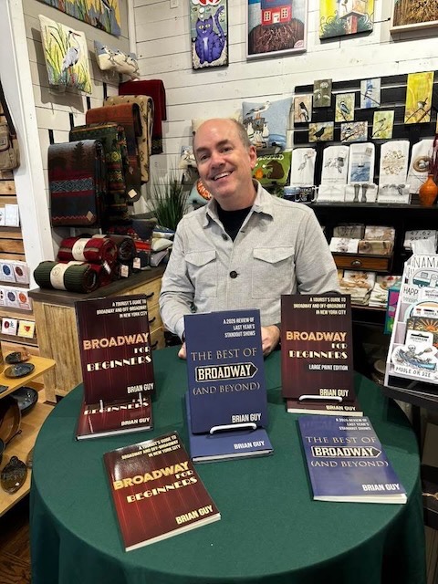 Brian Guy at a book signing table on Bainbridge Island, with copies of his books on display