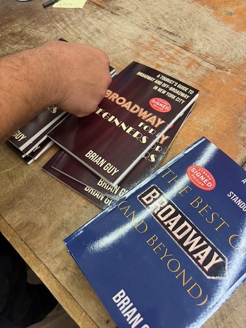 Brian Guy signing copies of his books, marked with Signed Copy stickers, at Strand Book Store